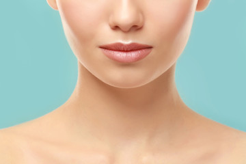 Closeup view of beautiful young woman with natural lips makeup on color background