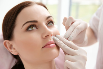 Woman having hair removal procedure on face with wax depilatory in salon. Depilation concept - obrazy, fototapety, plakaty