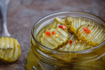 Slices of pickled cucumbers with pepper and mustard in a jar. Snack for gourmets. Selective focus