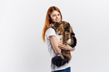 Fototapeta premium Beautiful young woman on a light background holds a cat, an allergy