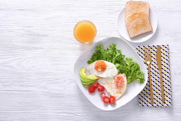Delicious breakfast with fried eggs on white wooden table