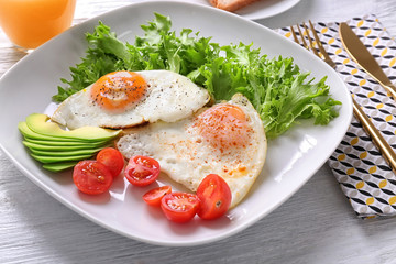 Delicious breakfast with fried eggs on white wooden table