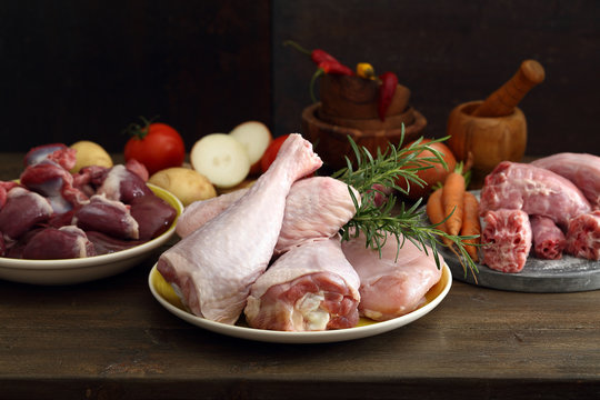 carne cruda di pollo o tacchino coscia cuore e collo  su tavolo di cucina rustico