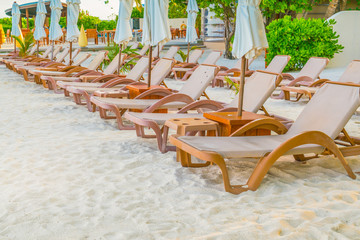 Beach chairs with umbrella at Maldives island, white sandy beach and sea .