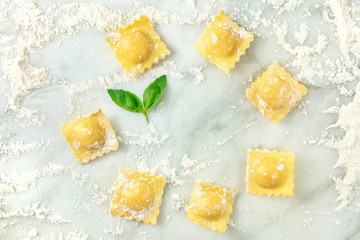 Overhead photo of ravioli with flour and basil leaves