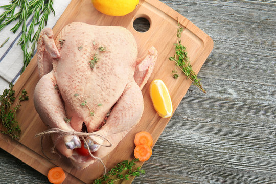 Composition with whole raw turkey and some products on wooden board