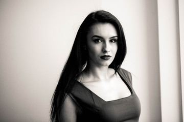 Beautiful young woman playing with her hair while leaning on the wall