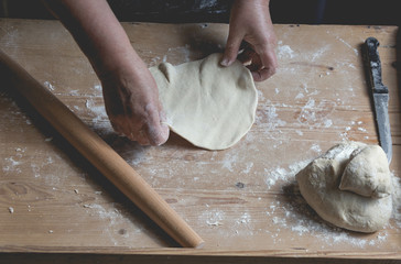 Senior woman roll fresh made pastry, preparing ingrediets for homemade croissants