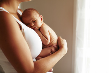 Mother holding her sleeping newborn baby boy