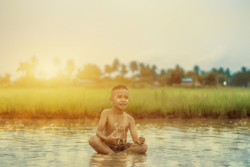 Fototapeta premium Asian Boy playing in water loosen hot looks happy, Before sunset background ,Thailand.
