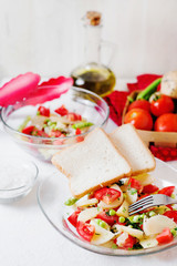 Tasty and healthy breakfast, lunch or dinner, potato salad with tomato, green peas, olive oil, spices and white toast on a light background 