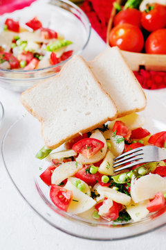 Tasty and healthy breakfast, lunch or dinner, potato salad with tomato, green peas, olive oil, spices and white toast on a light background 