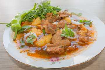 Beef stew served with cooked potatoes in a ceramic plate on a wooden background