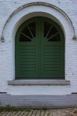 Very old window with green shutters in a white house