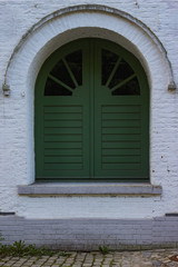 Fototapeta na wymiar Very old window with green shutters in a white house