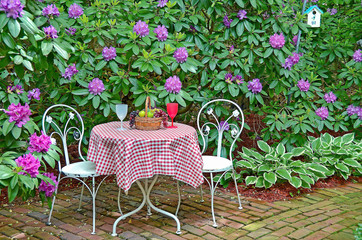 Fototapeta na wymiar fruit basket on table with chairs on brick patio in rhododendron garden