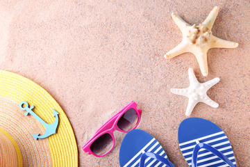 Fototapeta na wymiar Flip flops with starfish, sunglasses and hat on the beach sand