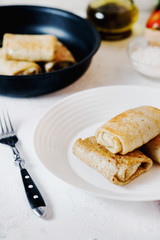 Hearty and delicious breakfast or lunch, thin pancakes filled with chicken with fresh vegetables, herbs and olive oil on a light background