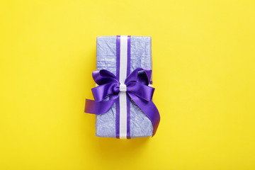 Gift box with ribbon on yellow background