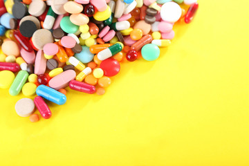 Different colorful pills on yellow background