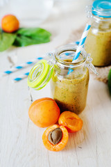 Healthy food, summer drinks, fruit and vegetable smoothie with banana, apricot and spinach in glass bottles on a light background, detox