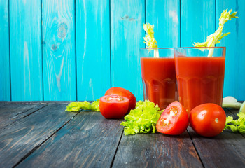 Tomato juice in glass with celery, tomato on wood background, closeup