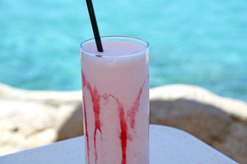 Milkshake made of fresh ripe strawberry on a sea background
