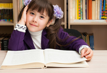 A girl at school at a lesson, in the library reading a book. The concept of education and upbringing