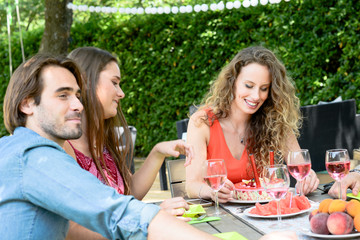 group of friends having fun picnic lunch party outdoor in backyard during summer holiday vacation