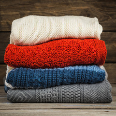 Multicolored sweaters stacked on a wooden surface