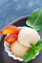 Peach ice cream and peach slices in a white bowl.