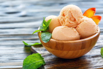 Balls peach ice cream in a wooden bowl.