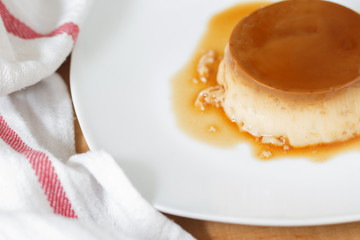 Creme caramel in a white dish and with a cotton napkin.