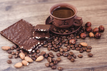 roasted coffee beans with chocolate and nuts on a wooden surface.