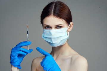 Beautiful young woman on a gray background holds a syringe, medicine, plastic surgery