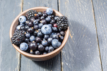 A variety of forest berries in a clay bowl.