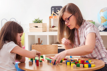 Preschool Teacher and Kid Playing with Wooden Building Blocks