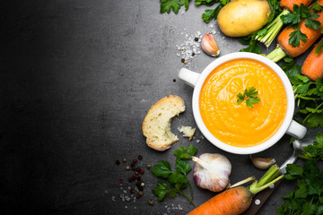 Carrot cream-soup on black table.