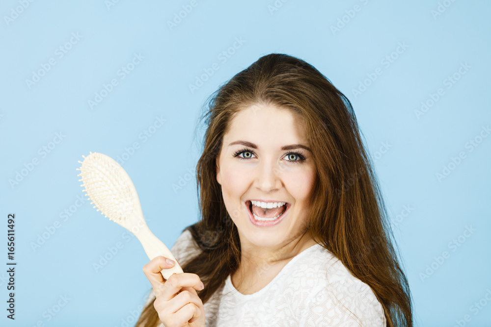 Wall mural Happy woman brushing her hair