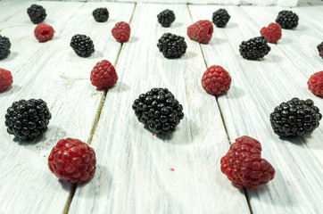 Blackberry and raspberries are arranged in a row. Front view.