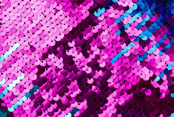 Sequins close-up macro. Abstract background with blue sequins and lilac color on the fabric. Texture scales of round sequins with color transition