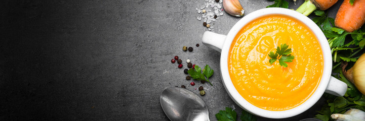 Carrot cream-soup on black table.