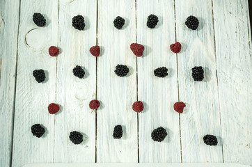 Blackberry and raspberries are arranged in a row. Flat lay.