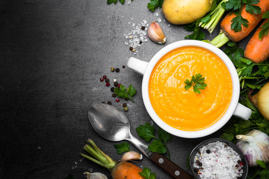 Carrot cream-soup on black table.