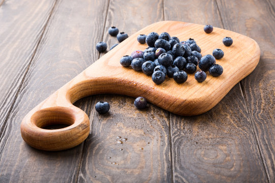 Fresh blueberries on cutting board on old wooden background. Healthy eating and nutrition concept with copy space.