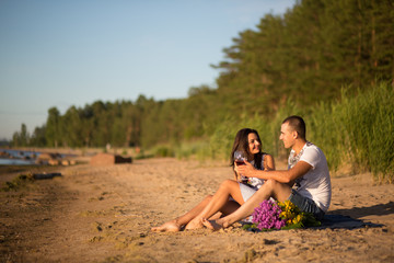 Naklejka premium A young couple in love, on the shore of the Bay at sunset