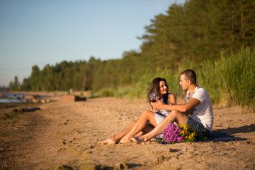 Fototapeta premium A young couple in love, on the shore of the Bay at sunset