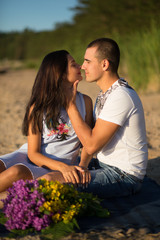 Naklejka premium A young couple in love, on the shore of the Bay at sunset