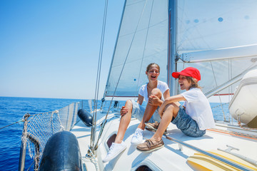 Brother and sister on board of sailing yacht on summer cruise. Travel adventure, yachting with...