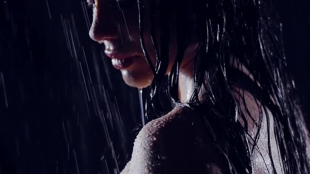 close-up portrait of a girl in the rain in the dark. in the face of flowing water. she was wet and naked